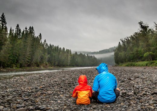 Kind und Erwachsener mit Regenjacken in der Natur