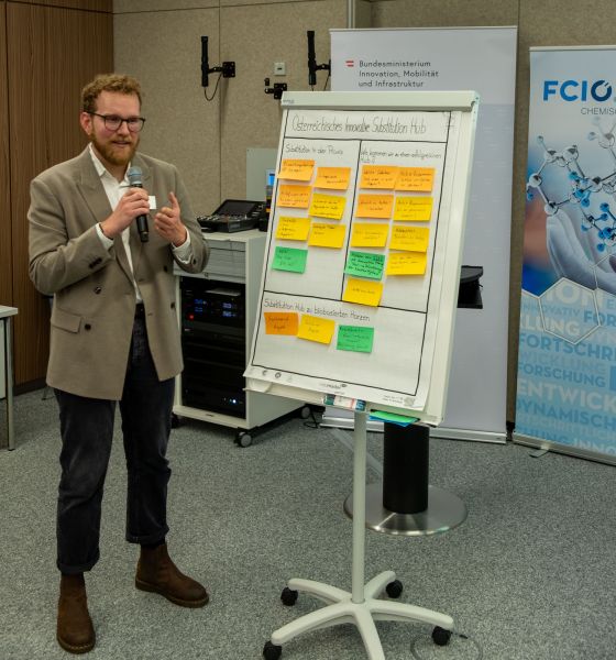 Ein Mann erklärt den Zuhörer:innen die Texte auf einem Flipchart