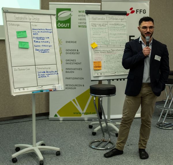 Ein Mann erklärt den Zuhörer:innen die Texte auf einem Flipchart